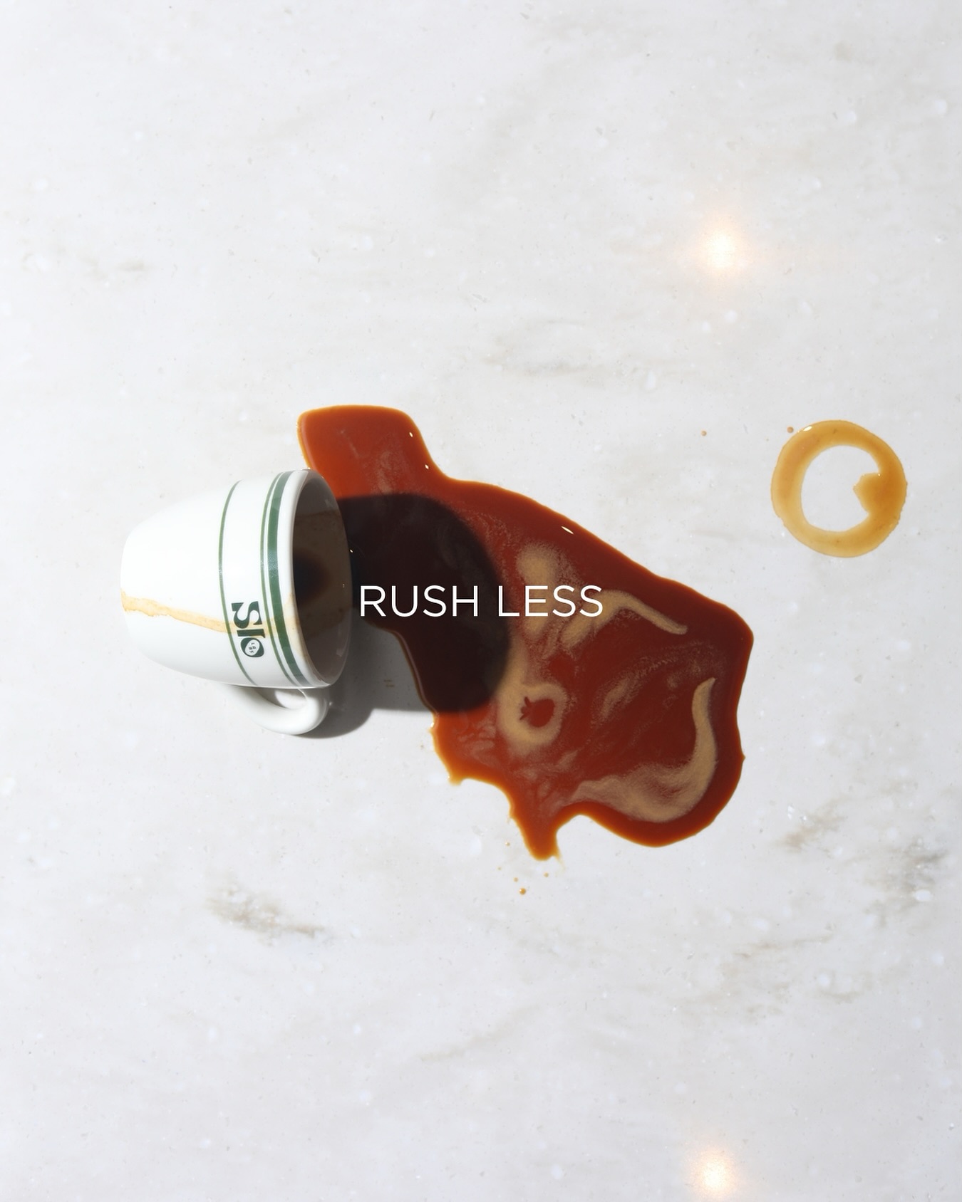 A spilled Slo Labs espresso cup on marble with the words rush less